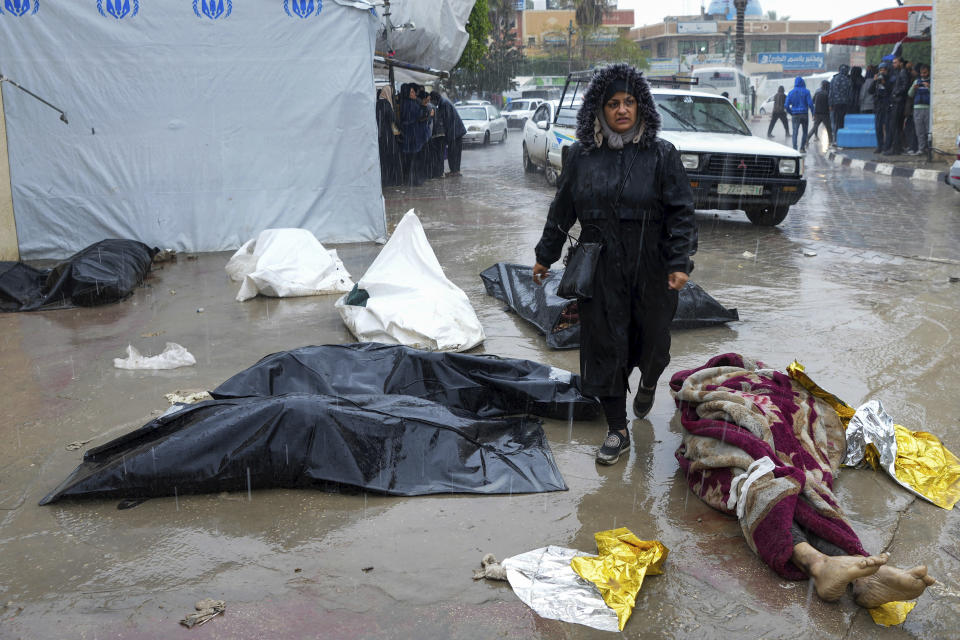 A woman walks between the bodies of Palestinians killed in the Israeli bombardments of the Gaza Strip, in front of the morgue at Al Aqsa Hospital in Deir al Balah, Gaza Strip, on Sunday, Feb. 18, 2024. (AP Photo/Adel Hana)