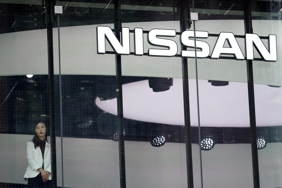 In this July 25, 2019, photo, a staff member stands by a window of a Nissan car gallery in Tokyo. Japanese automaker Nissan has seen July-September profit tumble to half of what it earned the previous year as sales and brand power crumbled since the arrest of former Chairman Carlos Ghosn a year ago. (AP Photo/Eugene Hoshiko)