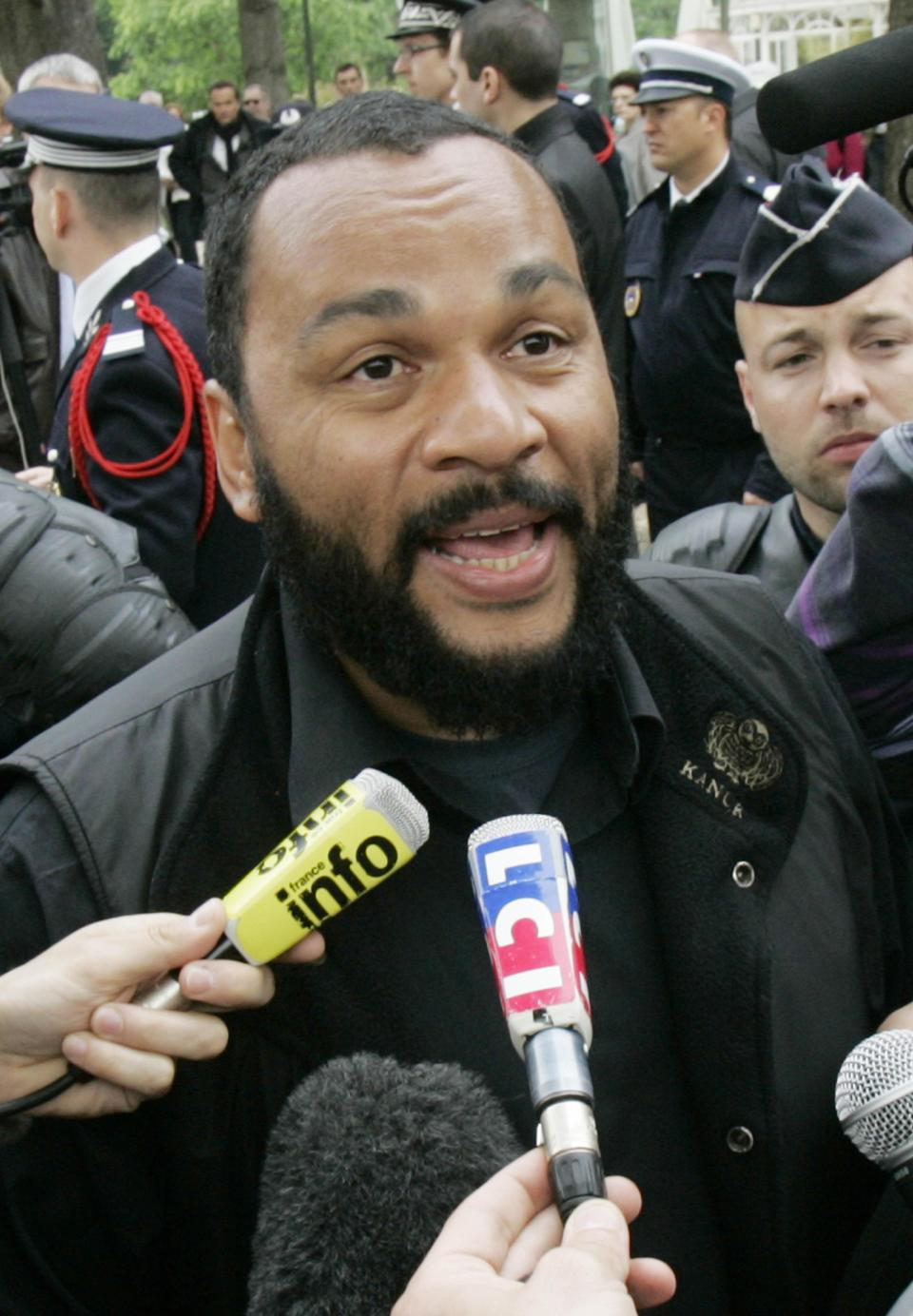 FILE - In this May 13, 2009 file photo, controversial French comic Dieudonne M'Bala M'Bala, known as Dieudonne, answers reporters as he heads for the interior Ministry to submit a list of candidates for the upcoming European elections, in Paris. The Paris prosecutor's office said Thursday Jan. 2, 2013, it is investigating threats against a comedian the French interior minister wants banned from the stage for what he says are racist and anti-Semitic performances. (AP Photo/Remy de la Mauviniere, File)