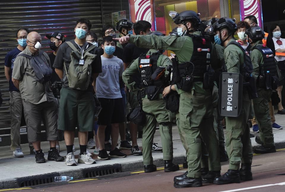 Police officers stand by the arrested people, left, at a downtown street in Hong Kong Sunday, Sept. 6, 2020. About 30 people were arrested Sunday at protests against the government's decision to postpone elections for Hong Kong's legislature, police and a news report said. (AP Photo/Vincent Yu) Vincent