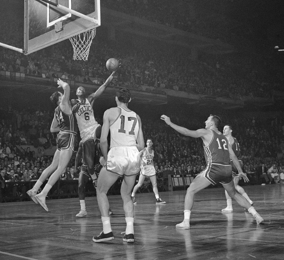 Bill Russell (6) of the Boston Celtics lays up a shot as Clyde Lovelletts (34) of the St. Louis Hawks attempts to block the play in their National Basketball Assn. playoff game at Boston Garden on April 5, 1960. Watching the action is Gene Conley (17) of the Celtics. AP Photo