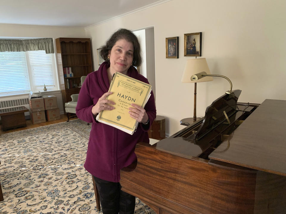 Anne D'Innocenzio stands by her family piano at her childhood home in suburban New Jersey, on April 3, 2023, hours before movers came to take it away to its new owner. D'Innocenzio sold her childhood home in late June of that year, a few months after her mother passed away. She had to say goodbye to more than a half century of memories. (Courtesy Anne D'Innocenzio via AP)