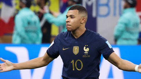 Kylian Mbappe celebrates his second goal at the 2022 World Cup, with his arms out.