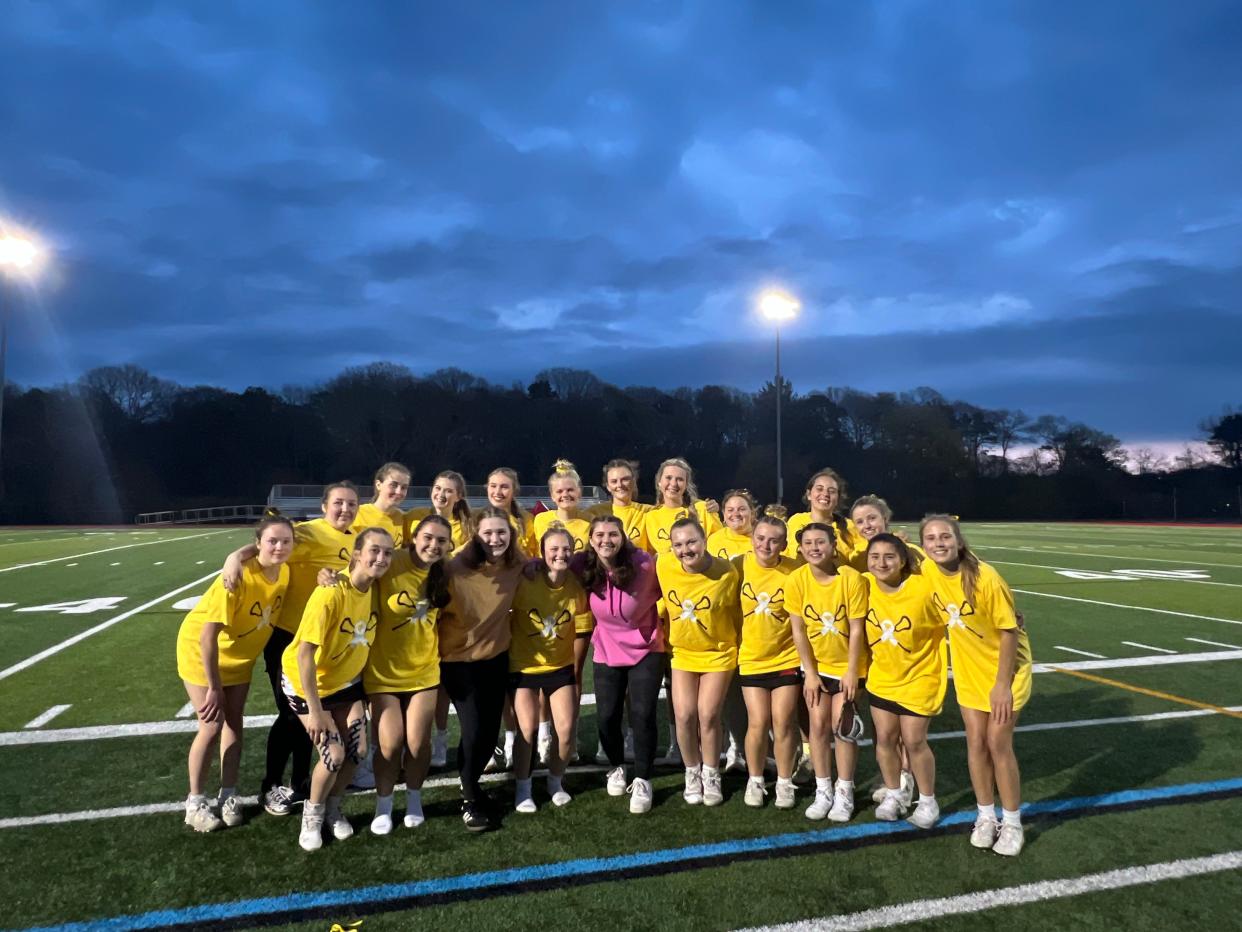 The Barnstable High School girls lacrosse team stands together, with Mayah White (left) and Emma DaSilver (right). Both girls have been diagnosed with cancer.