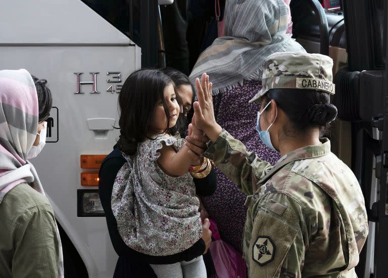 Kimberly Hernandez choca los cinco con una niña evacuada de Kabul, Afganistán, antes de abordar un autobús después de su llegada al Aeropuerto Internacional Washington Dulles, en Chantilly, Virginia