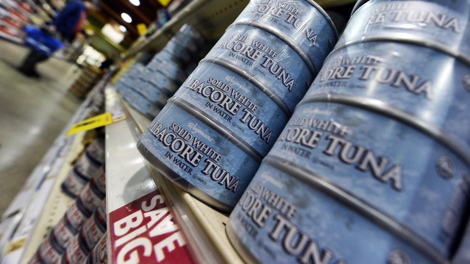 canned tuna are pictured as a man shops