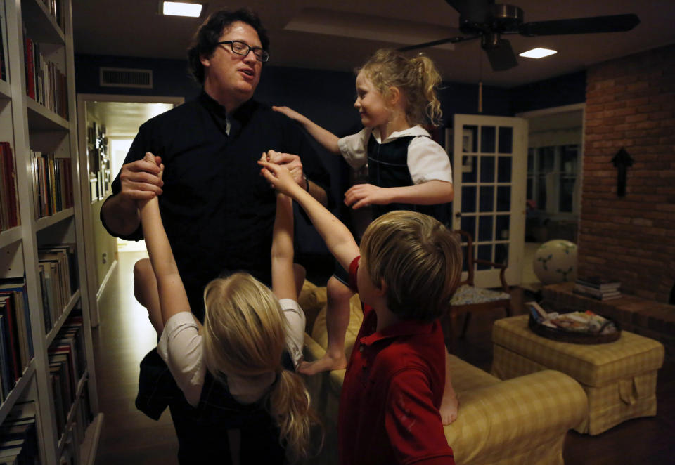 In this Feb. 7, 2020, photo, Catholic Priest, husband and dad Joshua Whitfield plays with three of his four children Maggie, 9, Peter, 8, and Zoe-Catherine, 5, at their home in north Dallas. (AP Photo/Jessie Wardarski)