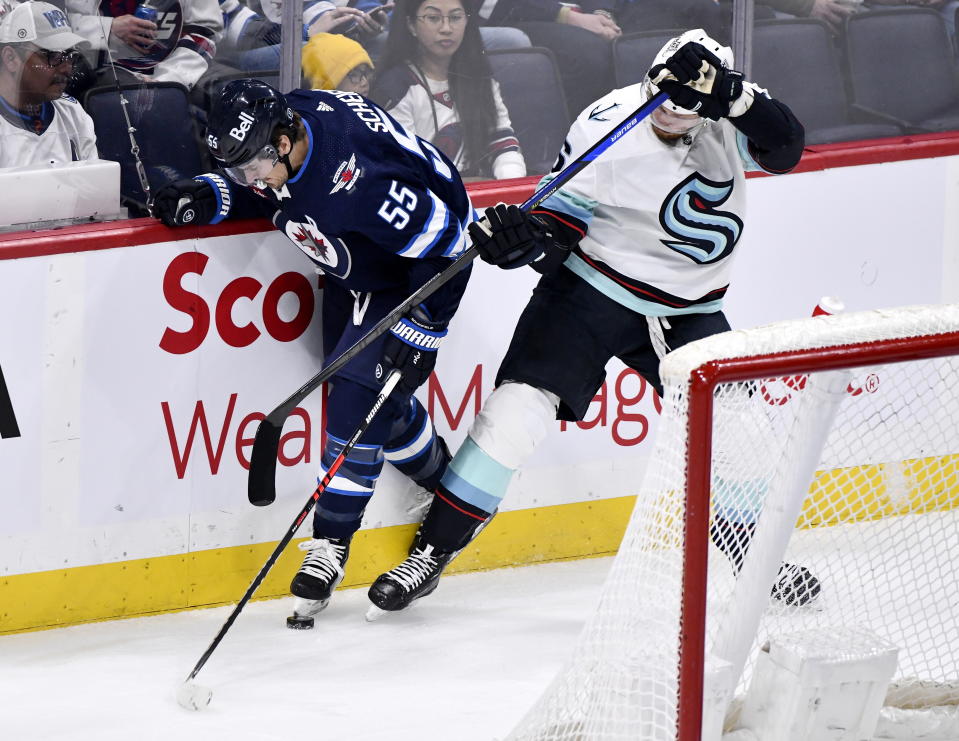 Seattle Kraken's Adam Larsson (6) and Winnipeg Jets' Mark Scheifele (55) battle for the puck during the first period of an NHL game in Winnipeg, Manitoba on Tuesday Feb. 14, 2023. (Fred Greenslade/The Canadian Press via AP)
