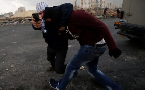 An undercover Israeli officer points a gun as he arrests a Palestinian man - Credit: REUTERS/Mohamad Torokman