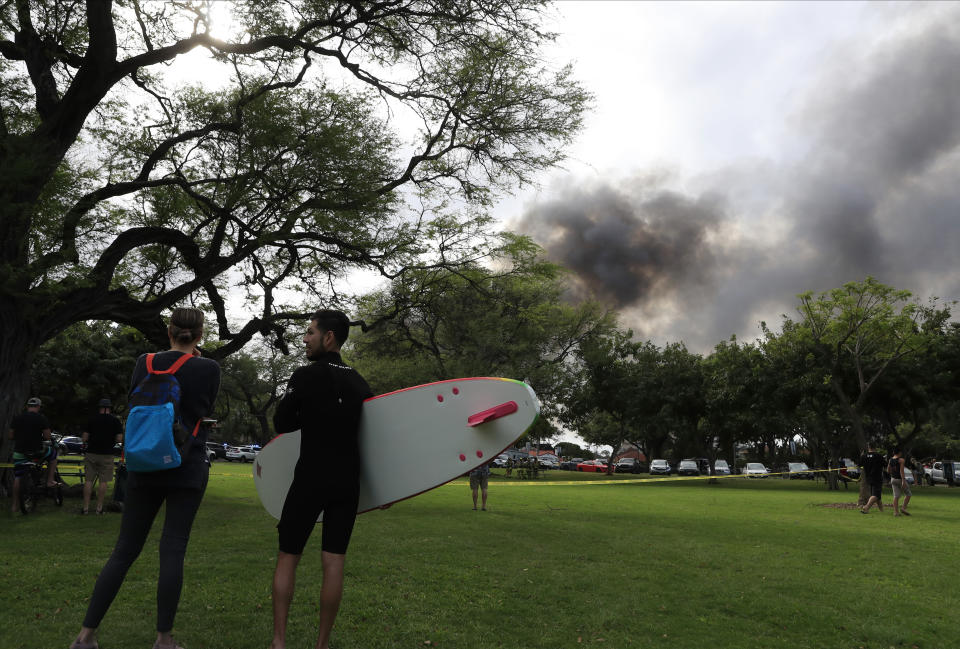 Aina Haina resident Kai Ohashi, right, and Waikiki resident Lucy Taylor observe billowing smoke from a house fire after a shooting and domestic incident at a residence on Hibiscus Road near Diamond Head on Sunday, Jan. 19, 2020, in Honolulu. Witnesses say at least two Honolulu police officers were shot and two civilians were injured. Moments after the shooting, the house was set on fire, possibly by the suspect. (Jamm Aquino/Honolulu Star-Advertiser via AP)