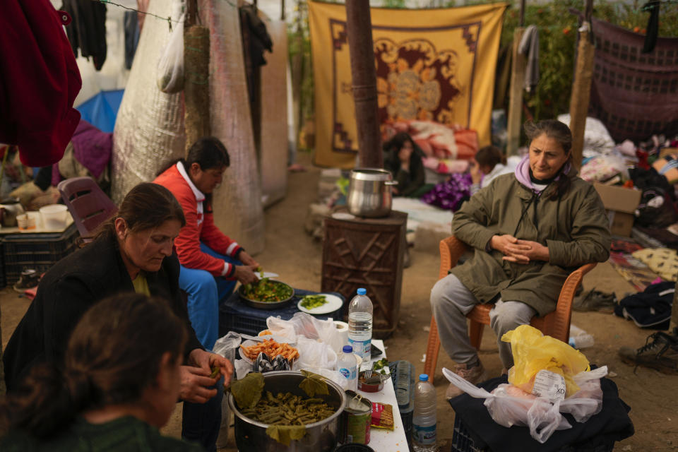 FILE - Women prepare a meal inside a greenhouse where they stay with their relatives following the earthquake in Samandag, southern Turkey, on Feb. 16, 2023. Hundreds of thousands of people are seeking shelter after the Feb. 6 earthquake in southern Turkey left homes unlivable. Many survivors have been unable to find tents or containers dispatched to the region by the government and aid agencies, Instead they have sought refuge in any structure that can protect them from the winter conditions, including greenhouses, rail carriages and factories. (AP Photo/Francisco Seco)