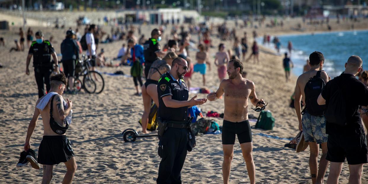 Police officers ask people to not sit while patrolling the beach in Barcelona, Spain, on Wednesday, May 27, 2020. Roughly half of the population, including residents in the biggest cities of Madrid and Barcelona, are entering phase 1, which allows social gatherings in limited numbers, restaurant and bar service with outdoor sitting and some cultural and sports activities. (AP Photo/Emilio Morenatti)