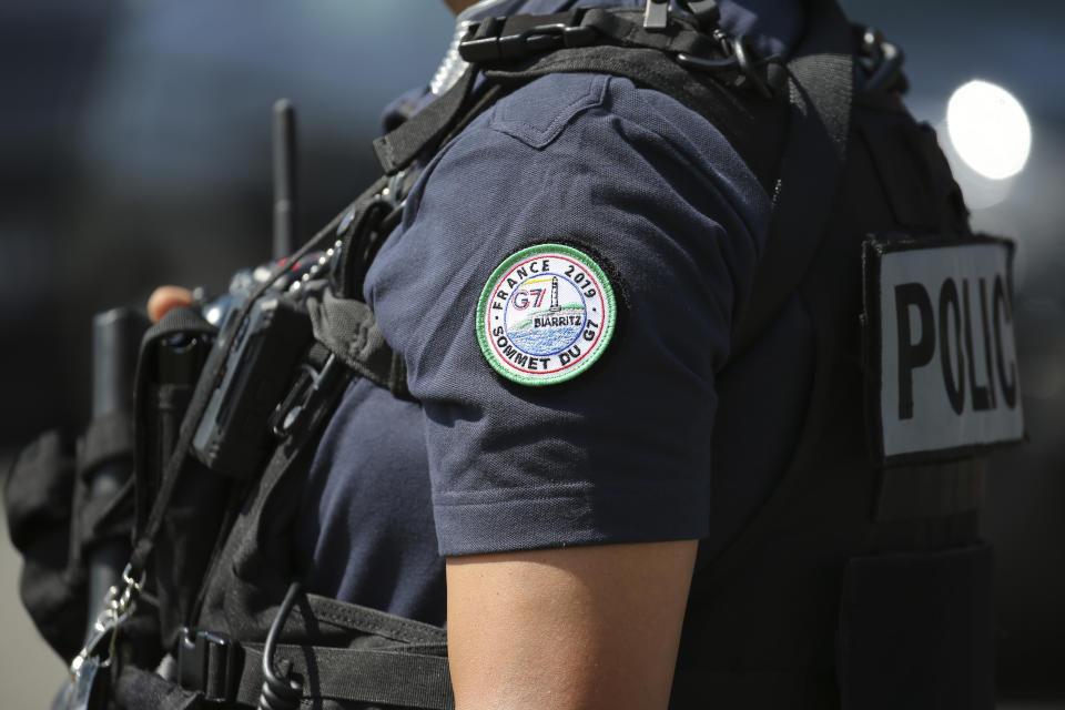 A police officers wearing a G7 badge stands guard while French Interior Minister Christophe Castaner visits the police command room ahead of the upcoming G7 summit, Tuesday, Aug.20, 2019 in Biarritz, southwestern France. French police are setting up checkpoints and combing Atlantic beaches to secure the southwestern coast for world leaders coming for the G-7 summit. (AP Photo/Bob Edme)