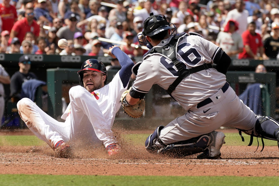 St. Louis Cardinals' Dylan Carlson, left, scores at the ball bounces past New York Yankees catcher Kyle Higashioka (66) during the eighth inning of a baseball game Sunday, July 2, 2023, in St. Louis. (AP Photo/Jeff Roberson)