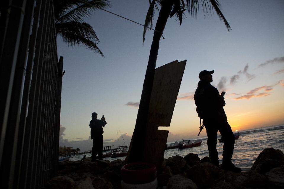 En esta fotografía del 17 de enero de 2017, policías municipales montan guardia durante el amanecer en una playa, afuera de la discoteca Blue Parrot, un día después de que una balacera dejara varias personas muertas en la madrugada en la localidad turística caribeña de Playa del Carmen, en México. Las autoridades mexicanas dijeron el martes que investigan si la balacera tuvo como motivo alguna extorsión, una venta callejera de drogas o una acción de asesinato. En la discoteca se efectuaba un festival de música electrónica cuando ocurrió el tiroteo, que dejó tres extranjeros y dos mexicanos muertos, según las autoridades. (AP Foto/Rebecca Blackwell)