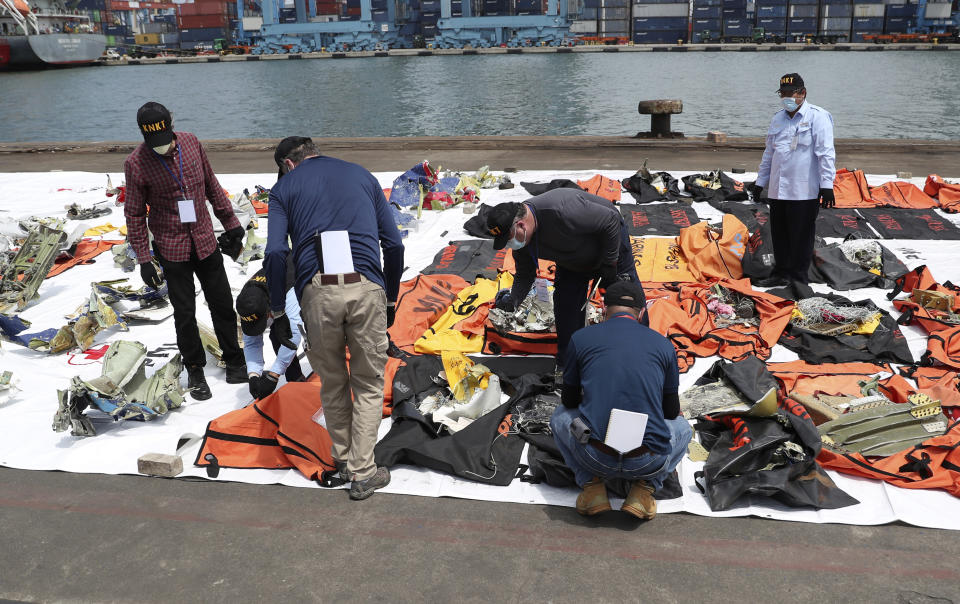 Members of the Indonesian National Transportation Safety Committee (KNKT) and U.S. National Transportation Safety Board (NTSB) investigators team inspect debris found in the waters around the location where a Sriwijaya Air passenger jet crashed, at the search and rescue command center at Tanjung Priok Port in Jakarta, Indonesia, Saturday, Jan. 16, 2021. (AP Photo/Achmad Ibrahim)