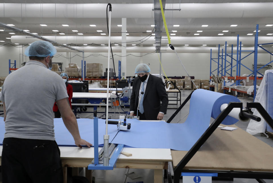 Britain's Prime Minister Boris Johnson, wearing a face mask to prevent the spread of the coronavirus, visits a PPE manufacturing facility during a visit to the north east of England, in Seaton Delaval, England, Saturday, Feb. 13, 2021. (AP Photo/Scott Heppell, Pool)