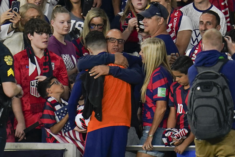 United States' Christian Pulisic, in orange top, is hugged by his father Mark Pulisic, center, after Christian Pulisic scored three goals in a FIFA World Cup qualifying soccer match against Panama, Sunday, March 27, 2022, in Orlando, Fla. The U.S. won 5-1. (AP Photo/Julio Cortez)