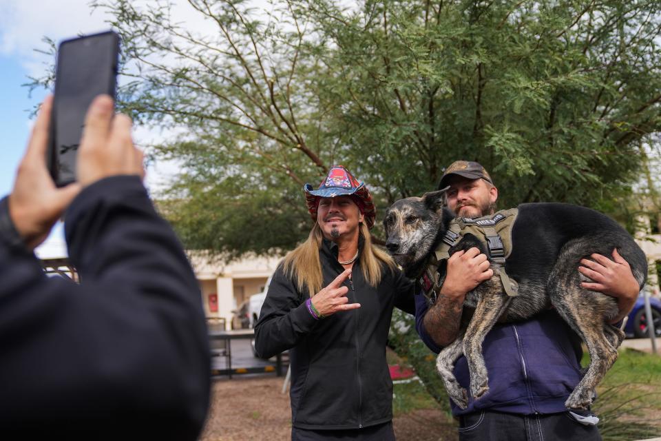 Bret Michaels, frontman for Poison, at center left, takes a photo with Jonathan Wilson, at right, and his dog Gunner, 6, during an event for homeless veterans at Grand Veterans Village on Thursday, Nov. 3, 2022, in Phoenix.