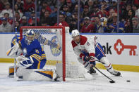 Montreal Canadiens defenseman Mike Matheson, right, loses the puck as he tries to wrap it around behind Buffalo Sabres goalie Eric Comrie during the first period of an NHL hockey game in Buffalo, N.Y., Monday, March 27, 2023. (AP Photo/Adrian Kraus)