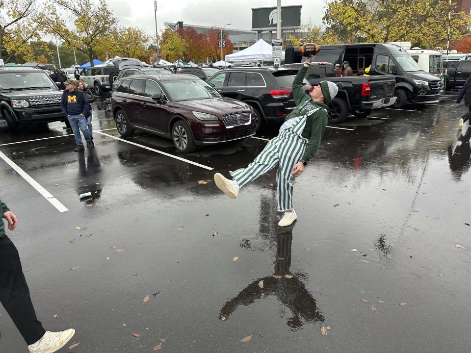 Michigan State University student Jack Bergman catches a football with one hand in a tailgating area outside Spartan Stadium before the Michigan-Michigan State NCAA college football game Saturday, Oct. 21, 2023, in East Lansing, Mich. According to a survey by The Associated Press of Power Five conference schools and Notre Dame, 55 of 69 of them sell alcohol in the public areas of their stadiums on game days. (AP Photo/Mike Householder)