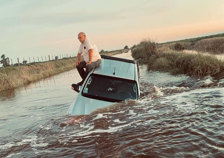 El productor Armando Rey sobre el techo de su camioneta, tapada por el agua en un camino rural que une Buenos Aires con Santa Fe