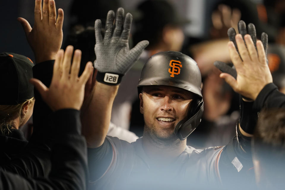 San Francisco Giants' Buster Posey celebrates his three-run home run with teammates in the dugout during the eighth inning of a baseball game against the Los Angeles Dodgers Friday, May 28, 2021, in Los Angeles. (AP Photo/Marcio Jose Sanchez)