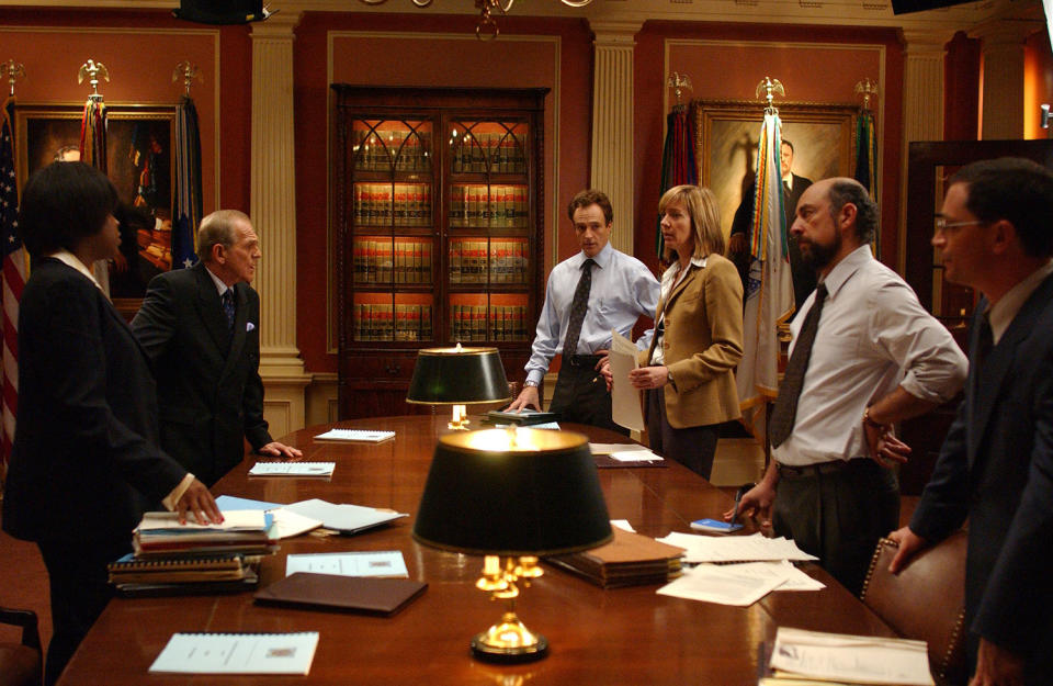 Michael Hyatt as Angela Blake, John Spencer as Leo, Bradley Whitford as Josh, Allison Janney as C.J., Richard Schiff as Toby and Joshua Malina as Will standing at conference table in S5 E8 of ‘The West Wing’ (Warner Bros.)