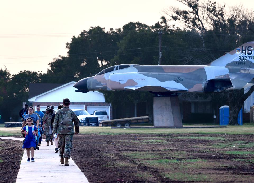 Students and parents walk past the jet fighter still on static display outside the former Dyess Elementary School as they make their way to the new building next door August 19, 2021. The display was eventually moved closer to the new school.