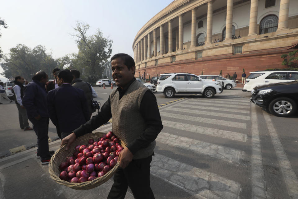 A Congress party worker carries a basket of onions used for a protest by party lawmakers against the rise in onion prices at the Parliament House, in New Delhi, India, Thursday, Dec. 5, 2019. The party protested outside Parliament against the government’s economic policies bringing down the country’s economic growth to 4.5%, its slowest pace in six years.. (AP Photo/Manish Swarup)