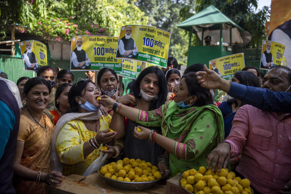 Members of India's ruling Bharatiya Janata Party (BJP) distribute sweets to celebrate 1 billion doses of COVID-19 vaccine in New Delhi, India, Thursday, Oct. 21, 2021. India has administered 1 billion doses of COVID-19 vaccine, passing a milestone for the South Asian country where the delta variant fueled its first crushing surge this year. (AP Photo/Altaf Qadri)