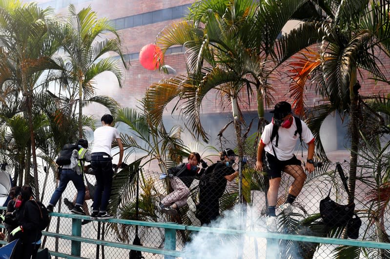 Protesters climb over the fence back to the campus of Hong Kong Polytechnic University (PolyU) after failing to leave, during clashes with police in Hong Kong