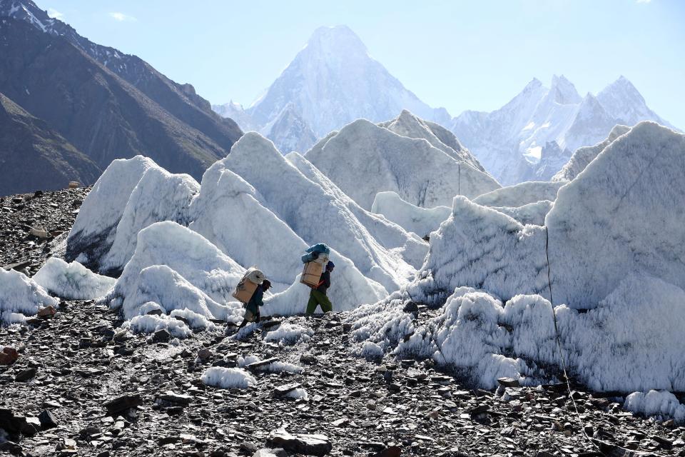 Pakistani porters hiking on the Baltoro Glacier along the trail between Askole and K2.