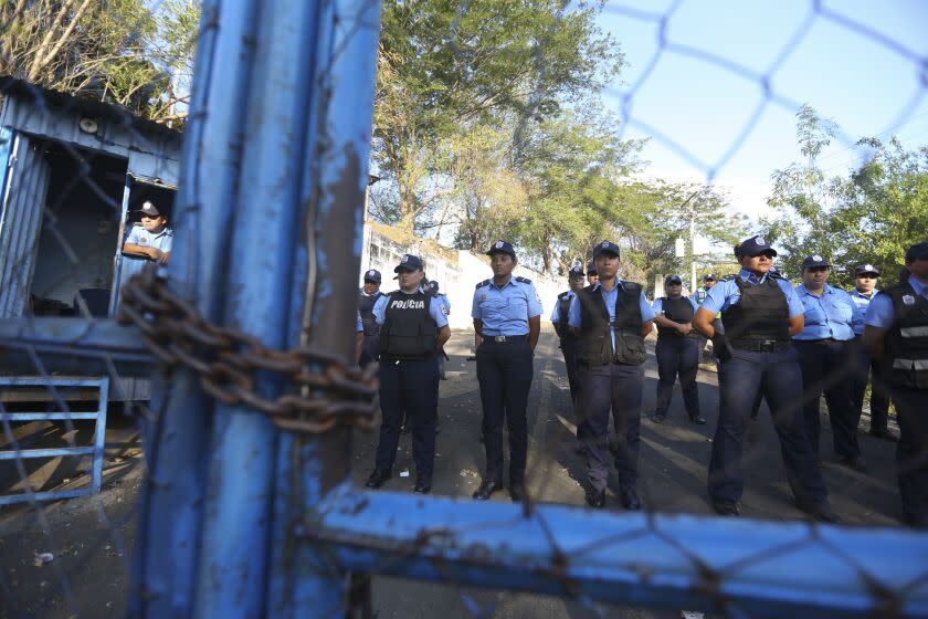 FILE - Police stand guard at a holding center known as "El Chipote," associated with torture during the Somoza dictatorship (1937-1979) and officially called the Judicial Assistance Directorate, as they face demonstrators, on the other side of the fence, protesting the arrests of anti-government protesters in Managua, Nicaragua, April 25, 2018. Some 222 inmates, considered by many to be political prisoners, were on a flight to Washington, D.C. on Feb. 9, 2023 after they were "unilaterally" released, according to a senior Biden administration official. (AP Photo/Alfredo Zuniga, File)