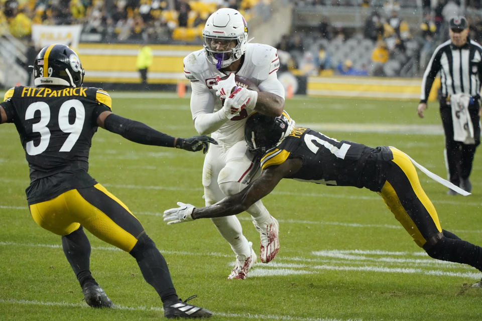 Arizona Cardinals running back James Conner, center, runs with the ball against Pittsburgh Steelers cornerback Joey Porter Jr., right, and Steelers safety Minkah Fitzpatrick (39) during the first half of an NFL football game, Sunday, Dec. 3, 2023, in Pittsburgh. (AP Photo/Gene J. Puskar)