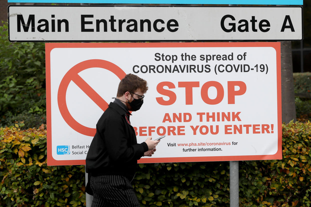 A man wearing a face mask walks past an entrance to Belfast City Hospital, in Northern Ireland, after the Stormont executive announced closures of schools, pubs and restaurants as the region enters a period of intensified coronavirus restrictions in response to spiralling infection rates. (Photo by Brian Lawless/PA Images via Getty Images)