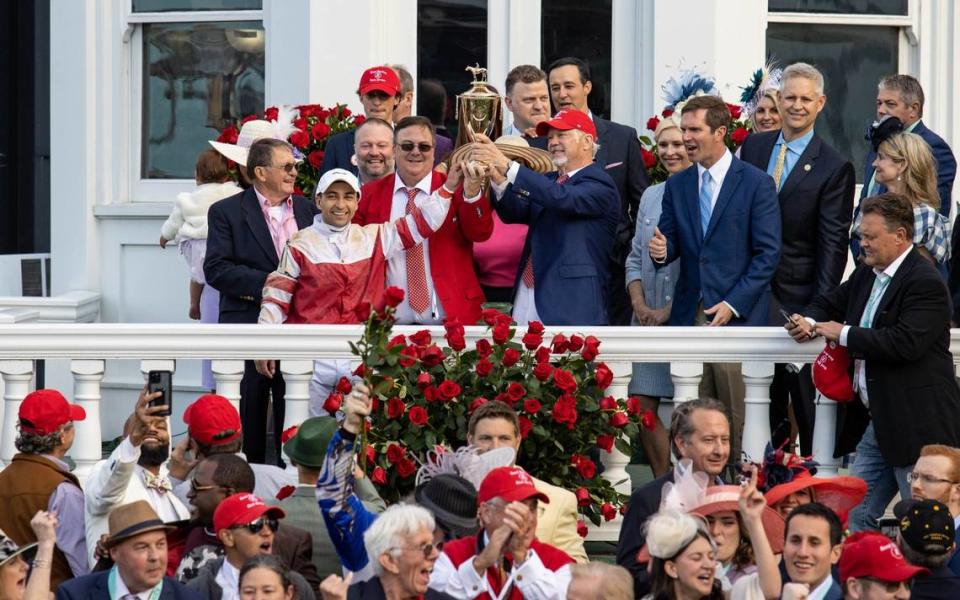 Rich Strike owner Richard Dawson, right, trainer Eric Reed, center, and jockey Sonny Leon, right, hold up the Kentucky Derby trophy after winning last year’s race at Churchill Downs. Dawson and Reed spoke last week about how the past year has gone since their horse’s victory as an 80-1 long shot in the Run for the Roses.
