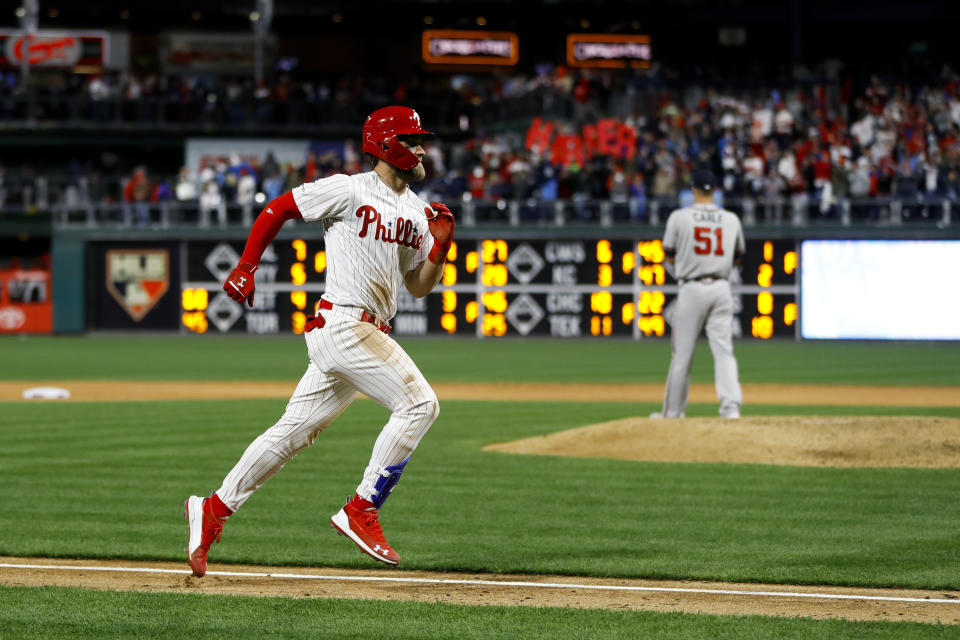 Philadelphia Phillies' Bryce Harper, left, rounds the bases after hitting a homerun off Atlanta Braves relief pitcher Shane Carle, right, during the seventh inning of a baseball game, Sunday, March 31, 2019, in Philadelphia. (AP Photo/Matt Slocum)