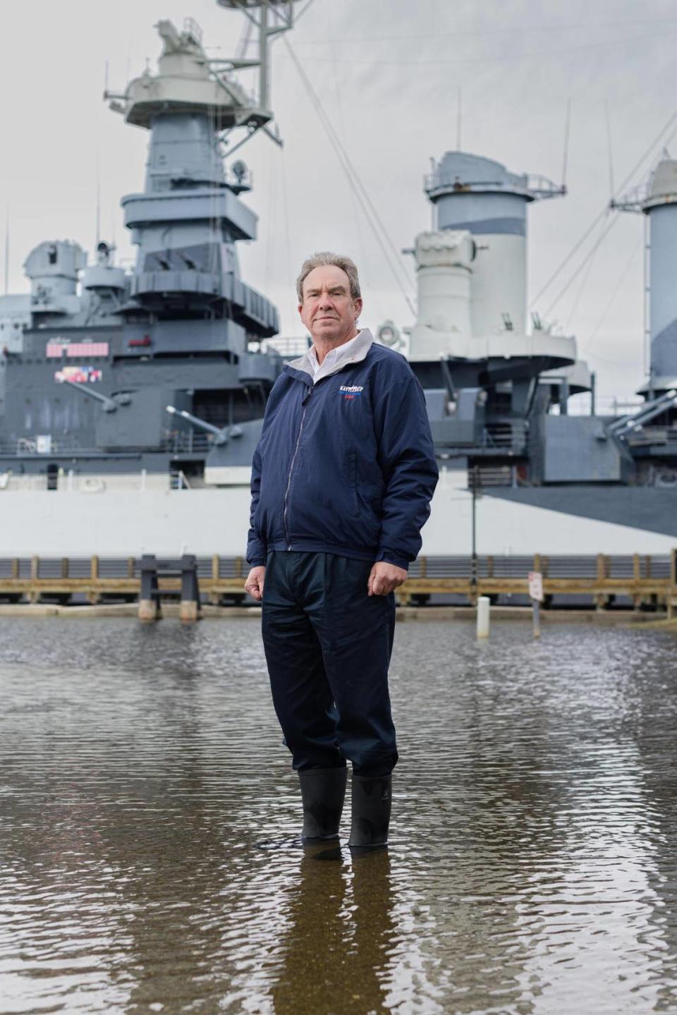 Retired U.S. Navy Capt. Terry Bragg, the executive director of the Battleship North Carolina museum, poses for a portrait in a flooded parking lot at the historic site in November.