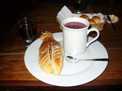 Colada Morada (derecha) servida junto una guagua de pan (izquierda). <a href="https://commons.wikimedia.org/wiki/File:Colada_morada.jpg" rel="nofollow noopener" target="_blank" data-ylk="slk:Juan Jorge Arellano / Wikimedia Commons;elm:context_link;itc:0;sec:content-canvas" class="link ">Juan Jorge Arellano / Wikimedia Commons</a>, <a href="http://creativecommons.org/licenses/by-sa/4.0/" rel="nofollow noopener" target="_blank" data-ylk="slk:CC BY-SA;elm:context_link;itc:0;sec:content-canvas" class="link ">CC BY-SA</a>