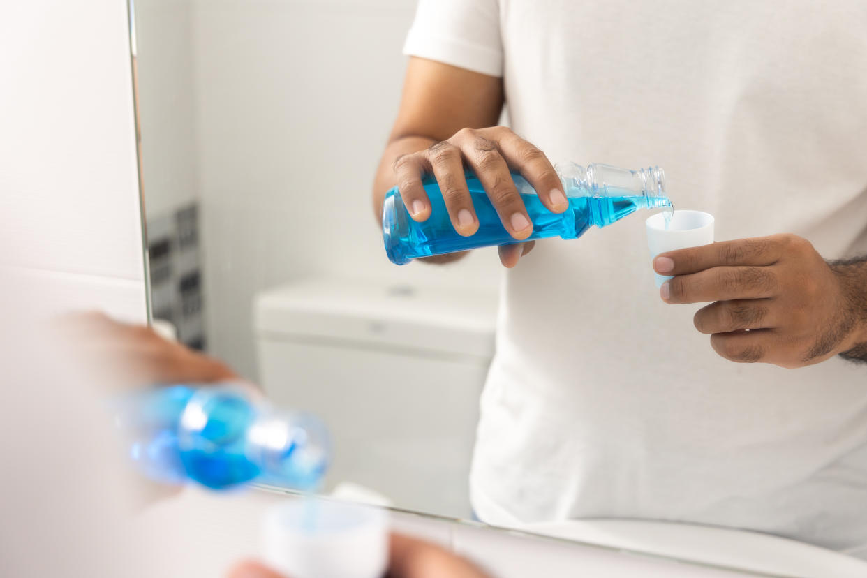 Young man is gargling with a blue mouthwash. For good dental health and fresh bad breath