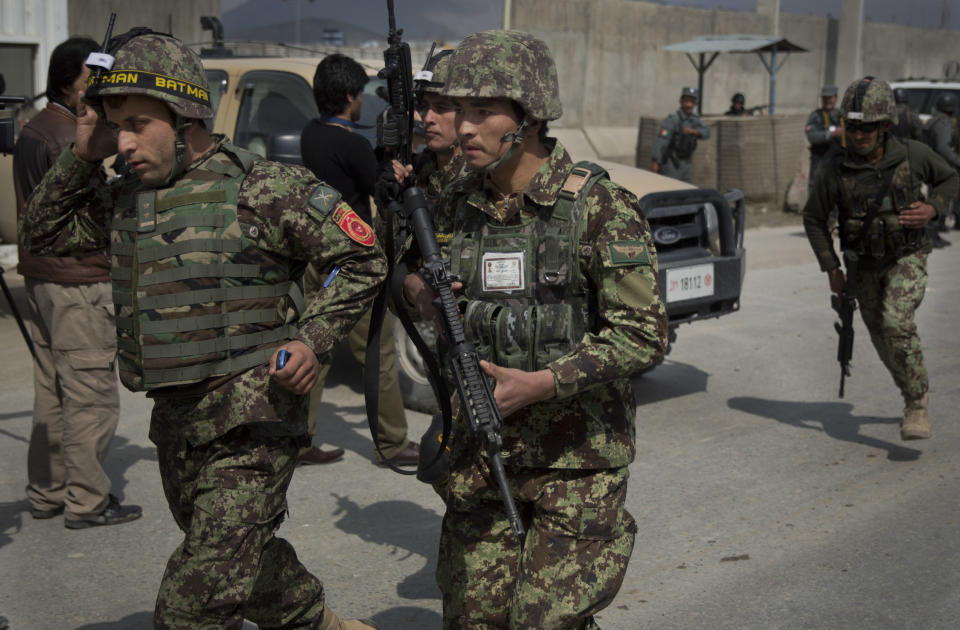 Afghan soldiers rush to the scene as Taliban militants attacked the main Afghan election commission's headquarters in the outskirts of Kabul, Afghanistan, firing on the compound with rocket-propelled grenades and heavy machine guns from a house outside its perimeter wall, Saturday, March 29, 2014. Dozens of employees and other people who had been inside the Independent Election Commission compound took cover in the basement, and no casualties were reported. But two warehouses were hit and set on fire, witnesses said. (AP Photo/Anja Niedringhaus)