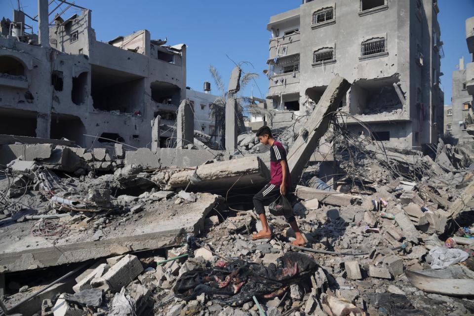 Palestinians stand by the building destroyed in an Israeli airstrike in Deir al-Balah, south of the Gaza Strip, Saturday, Oct. 14, 2023. 