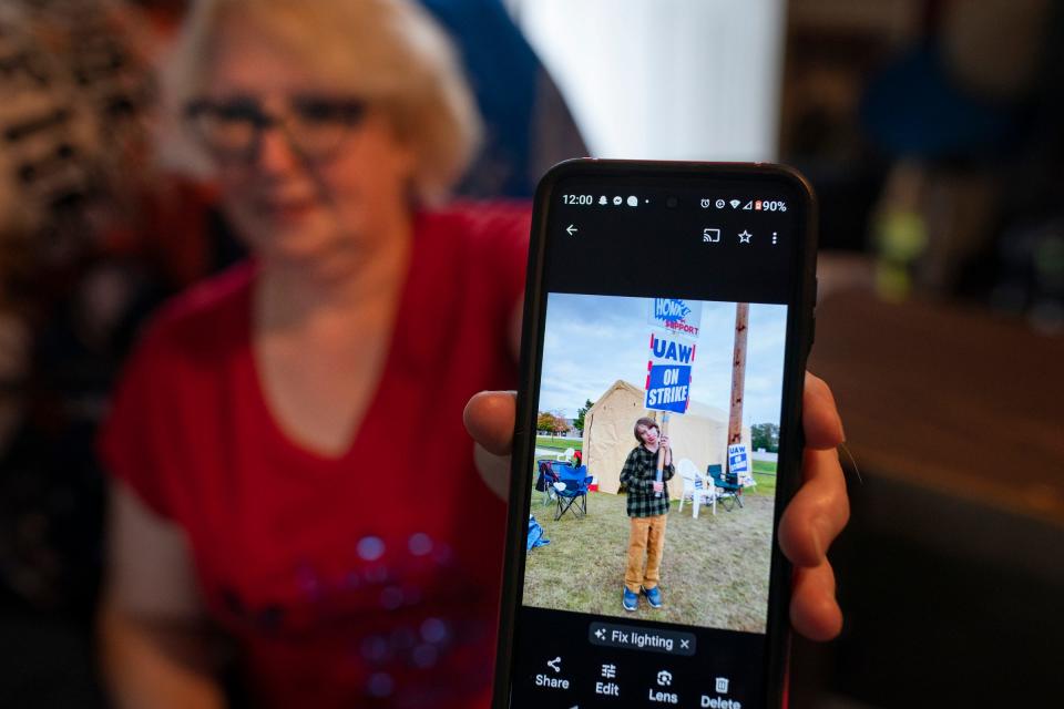 Annette Kramer, 54, holds up a photo on Monday, Oct. 16, 2023 in her Corunna living room of her grandson Kire Dumont, 10, who worked the picket line with her recently. Kramer has been on strike at GM in Lansing since Sept. 22 and is juggling bills and cutting back.