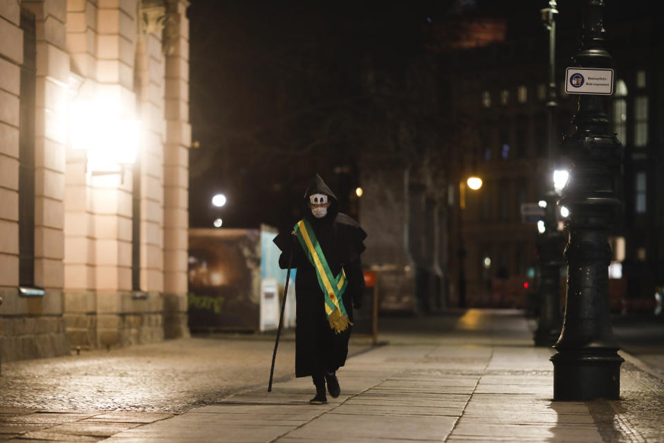 Brazilian activist and artist Rafael Puetter, dressed as the grim reaper, walks in a one-man protest through Berlin, Germany, early Wednesday, April 7, 2021. The multimedia artist starts his performance at the Brazilian embassy in Berlin at midnight every night to protest against Brazil's COVID-19 policies. Rafael Puetter walks to the Brandenburg Gate and then to the nearby German parliament building, in front of which he counts out a sunflower seed to represent each of the lives that were lost over the past 24 hours in Brazil because of the coronavirus pandemic. (AP Photo/Markus Schreiber)