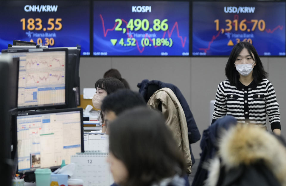 A currency trader passes by the screens showing the Korea Composite Stock Price Index (KOSPI), center, and the foreign exchange rate between U.S. dollar and South Korean won, right, at the foreign exchange dealing room of the KEB Hana Bank headquarters in Seoul, South Korea, Thursday, Dec. 7, 2023. Shares fell Thursday in Asia after a retreat on Wall Street as crude oil prices slipped on expectations that supply might outpace demand. (AP Photo/Ahn Young-joon)