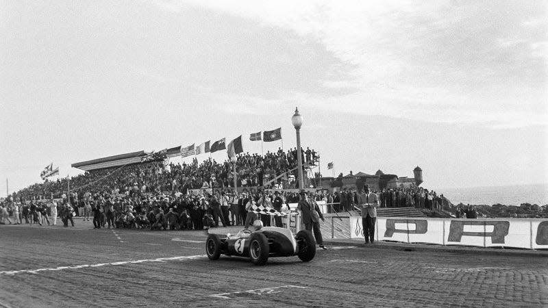 A black and white photo of Jack Brabham racing in F1. 