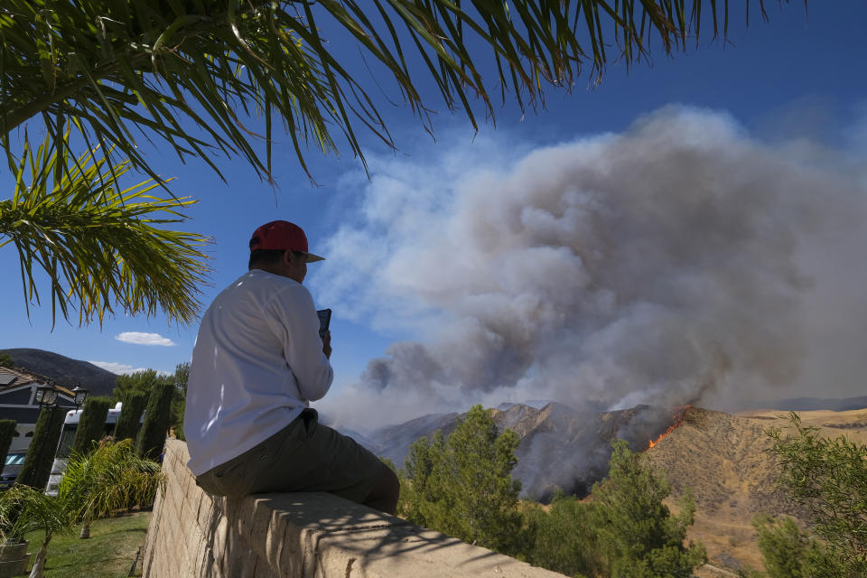 A man watches as smoke rises from a wildfire in Castaic, Calif., on Wednesday, Aug. 31, 2022. (AP Photo/Ringo H.W. Chiu)