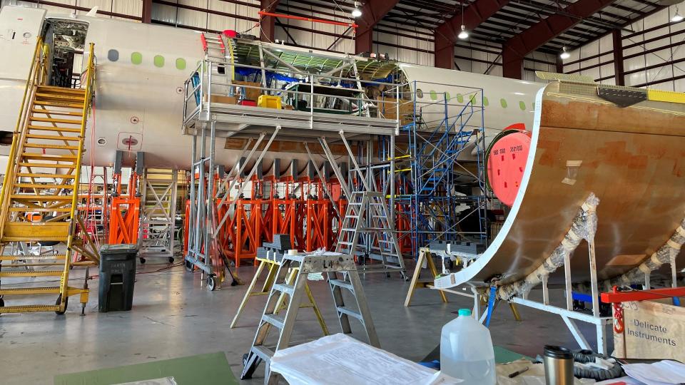 A view of an airframe repair shop with the plane on a stand as it gets overhauled into a cargo jet.