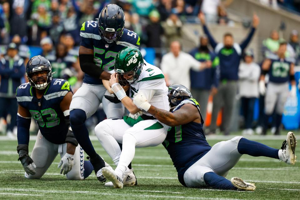 Seattle Seahawks defensive end Darrell Taylor (52) and defensive tackle Quinton Jefferson (77) sack New York Jets quarterback Mike White (5) on Jan. 1, 2023, in Seattle.